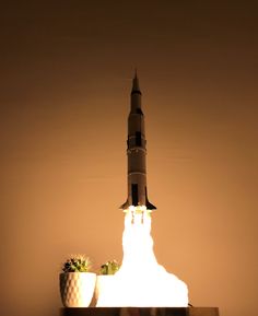 a rocket launching into the sky with two planters on it's side and one being lit up