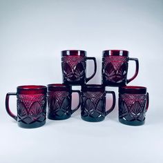 six red glass mugs sitting next to each other