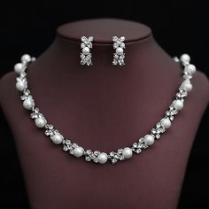 a necklace and earring set with pearls on a mannequin neckline in front of a black background