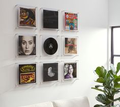 a white couch sitting next to a wall filled with pictures and vinyl record's