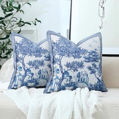 two blue and white pillows sitting on top of a couch