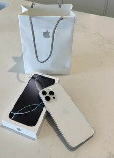 two white iphones sitting next to each other on a table in front of a bag