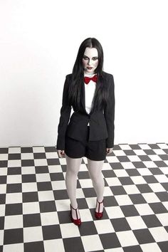 a woman dressed in black and white is standing on a checkered floor