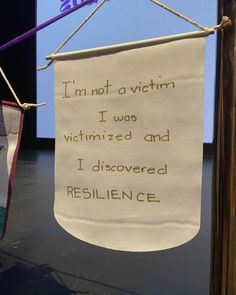 a sign hanging from a rope with writing on it that reads, i'm not a victim i was determined and i discovered resilince