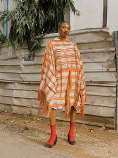 Winner of the CNMI Sustainable Fashion Awards for Emerging Designers—Nkwo Onwuka celebrates her Nigerian heritage in every piece. This orange and beige poncho is made from locally spun cotton yarn and woven by hand on traditional looms. It has a loose fit, wide sleeves, and swishy fringing for an extra touch of carefree cool. - Fringe trims, wide open sleeves- Cotton- Created by local artisans using innovative waste-reduction practices, such as recycling and fabric manipulation- Each piece is ma African Luxury, Abuja Nigeria, Waste Reduction, Open Sleeves, Red Carpet Ready, Open Sleeve, Fashion Awards, Dress Crafts, Local Artisans