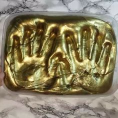 someone is holding out their handprints in a plastic container with gold foil on it