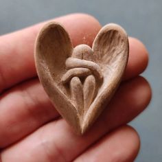 a small wooden heart shaped object in someone's hand