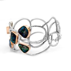 "This is the perfect gift for cuff lovers! It is a 14 karat, two tone, gold wide cuff, with six abstract shaped Boulder Opals bezel set in rose gold. The Opals have blue, green, pink hues. This cuff is from our \"Opalescence collection\". Each stone is unique in color and shape. [MATERIAL] Center Stone: Boulder Opal Cut: Cabochon Clarity: slight imperfections Play of color: blue, green, pink hues Transparency: Opaque Origin: Queensland Australia Type: Boulder Carat: 26.01 Metal: 14 karat two ton Luxury Open Band Cuff Bracelet As Gift, Luxury Open Band Cuff Bracelet For Gift, Luxury Open Band Bangle For Gift, Luxury Open Band Bangle As Gift, Elegant Bangle With Unique Design, Elegant Bangle Bracelets With Unique Design, Luxury Oyster Cuff Bracelet As Gift, Unique Adjustable Multi-stone Cuff Bracelet, Luxury Blue Cuff Bracelet With Patina