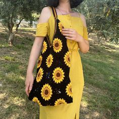 a woman in a yellow dress holding a black crocheted sunflower purse