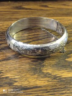 "Super Quality Niello Silver Siam Bangle. As the piece is marked Siam Sterling, it would indicate that it was made pre 1949. Nielloware jewellery were popular gifts from American soldiers taking \"R&R\" in Thailand to their girlfriends/wives back home from the 1930s to the 1970s. Most of it was completely handmade jewellery. The technique is as follows: The artisan would carve a particular character or pattern into the silver, leaving the figure raised by carving out the \"background\". He would then use the niello inlay to fill in the \"background\". After being baked in an open fire, the alloy would harden. It would then be sanded smooth and buffed. Finally, a silver artisan would add minute details by hand. Filigree was often used for additional ornamentation. Nielloware is classified a Antique Jewelry With Hallmarks For Anniversary, Antique Hallmarked Cuff Bracelet For Ceremonial Use, Vintage Silver Round Jewelry, Victorian Engraved Bangle For Gift, Collectible Hallmarked Bracelet Jewelry, Heirloom Oval Engraved Bracelets, Vintage Collectible Bangle Jewelry, Victorian Jewelry For Wedding With Hallmarks, Collectible Hallmarked Bracelet