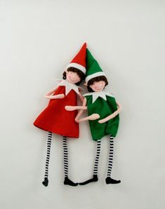 two elf dolls standing next to each other with their arms around the same person's head