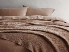 an unmade bed with brown linens and pillows