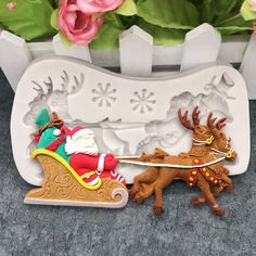 a santa clause riding on a sleigh being pulled by reindeer figurines