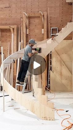 a man standing on top of a ladder working on some wooden planks in a building