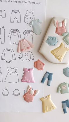 the paper doll is next to some baby clothes and shoes on it's surface