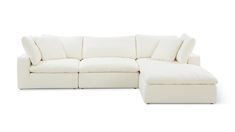 a white sectional couch with pillows on it's back and side facing the sofa