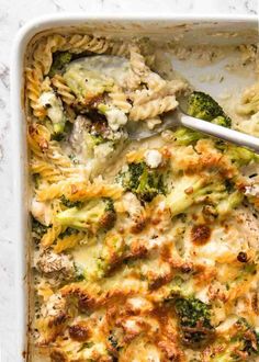 a casserole dish with broccoli, chicken and cheese in it next to a spoon