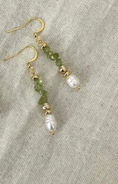 Statement Peridot & Pearl Cascade Dangle Earrings  Designed to make a statement, these bold dangle earrings bring elegance to any outfit. Handmade with genuine peridot stones, freshwater pearls, and gold-plated accents, they're perfect for those moments when you want to feel extra special. Whether it's a wedding, a holiday party, or a romantic evening out, these earrings will turn heads and add a touch of sophistication to your look.                               From Our Timeless Peridot & Pearl Collection                                                  Crystal Cascade Earrings * Product   Detail * - Crystal quartz, green glass bead, freshwater pearl - Clasp: Fishhooks - Gold-plated  - Style: Vintage-inspired, holiday-ready elegance - Tarnish - Resistance - Handmade and made to order - L Cascade Earrings, Dainty Dangle Earrings, Pearl Clasp, Jewelry Holiday, Vintage Inspired Jewelry, Peridot Stone, Pearl Collection, Romantic Evening, Homemade Jewelry