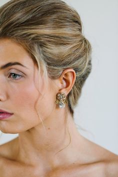 a woman with blonde hair and earrings on her head looking off to the side,