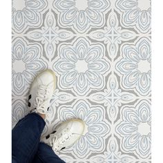 someone is standing on the floor in front of a wall with blue and white tiles