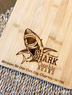 a wooden cutting board with a shark on it's side that says, beware of the shark cook like eat