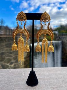 Jhumkas are a popular earring style in India and other South Asian countries. They are often crafted with a gold or silver finish and commonly adorned with pearls or gemstones. Jhumkas typically feature a large teardrop-shaped pendant that hangs from the earlobe, with smaller pendants dangling from the bottom of the main pendant. These earrings are known for their striking and elaborate design. Temple Jewelry Style Chandbalis With Latkans, Temple Jewelry Chandbalis With Latkans, Gold Plug Earrings For Festive Celebration, Festive Gold Plug Earrings For Celebration, Temple Jewelry Bridal Earrings With Latkans, Temple Jewelry Style Bridal Earrings With Latkans, Festive Celebration Gold Plug Earrings, Festive Gold Plug Earrings With Latkans, Festive Gold Chandbali Plug Earrings