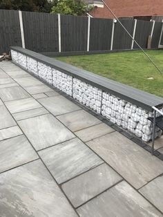 a bench made out of tennis balls sitting on top of a stone floor next to a fence