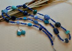 This 36 inch necklace is made from small dark blue beads with other larger beads in turquoise, light blue, and dark blue. There are also silver accent beads. It has a small toggle clasp. The matching earrings are included. This long necklace will look great with blues, white, black and beige. It is very versatile. Bohemian Blue Beaded Bracelets With Oval Beads, Adjustable Blue Multi-strand Jewelry, Adjustable Multi-strand Blue Jewelry, Blue Multi-strand Gemstone Beads Bracelets, Blue Multi-strand Bracelets With Gemstone Beads, Blue Oval Faceted Bead Jewelry, Blue Multi-strand Hand-strung Beads, Blue Beaded Dangle Necklaces With Natural Stones, Blue Beaded Necklaces With Natural Stones And Dangle Shape