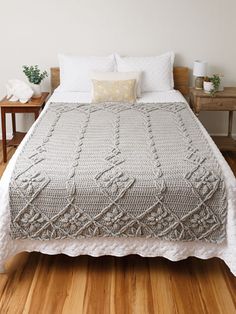 a bed with a blanket and pillows on top of it in a room that has wood floors