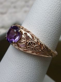 Natural Purple Amethyst Gold Ring Etched Wedding Design#160 Custom This stunning Victorian vintage reproduction ring in 10k rose gold has a brilliant natural purple amethyst gemstone. This full cut round cut genuine amethyst is 6mm in diameter. The inside of the band is marked 10k for gold. Notice the beautiful floral design of the gold filigree setting. This is a lovely rendition of an Antique filigree wedding ring. Make a spectacular statement about love and romance with this glorious solitair Amethyst Wedding Ring Stamped 14k, Wedding Amethyst Ring Stamped 14k, Vintage Oval Amethyst Ring For Wedding, Vintage Oval Amethyst Wedding Ring, Amethyst Rings With Intricate Design For Wedding, Gold Amethyst Ring For Wedding, Gold Amethyst Ring For Wedding, Round Cut, Heirloom Gold Amethyst Ring For Weddings, Antique Hallmarked Amethyst Wedding Ring