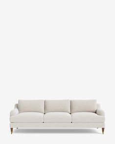 a white couch sitting on top of a wooden floor next to a wall with a light colored background