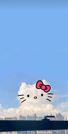 an image of a hello kitty on the side of a building with clouds in the background