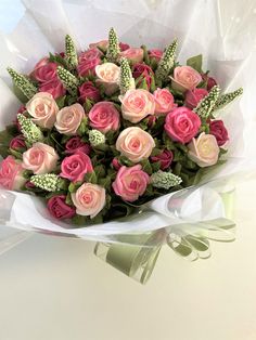 a bouquet of pink and white roses wrapped in paper