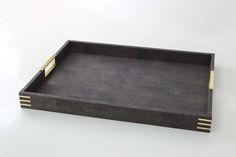 a black tray with gold handles on a white surface