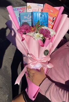 a person holding a bouquet of flowers and books