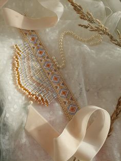 an assortment of bead and ribbon on a white lace tablecloth with wheat stalks in the background