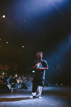 a person standing on a stage holding a drink in front of an audience at a concert