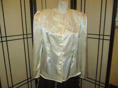 "Soft and feminine ivory satin blouse by Milani Petite is @ 1980's. 100% polyester. Hand wash or dry clean.  Button down with faux pearl buttons The wide collar is sheer with embroidery and faux pearls. Large shoulder pads. Fitted at the waist. Size 12. It measures 23\" long. 15 1/2\" across the top of the shoulders. 23 1/2\" sleeves. Laying flat seam to seam it's 20\" across under the arms, 16 1/2\" at the waist.  Practically like new. The only issue I can find is a tiny spot on the back side o Spring Satin Blouse With Buttons, Satin Blouse With Buttons For Spring, Spring Wedding Button-up Blouse, Cream Satin Top For Formal Occasions, Cream Satin Tops For Formal Occasions, Formal Cream Satin Top, Evening Satin Blouse With Buttons, Formal Satin Blouse With Buttons, Cream Satin Long Sleeve Blouse