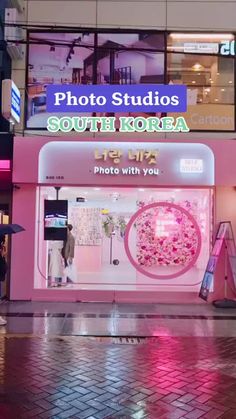 a pink store front on the corner of a city street at night with people walking by