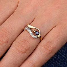 a woman's hand wearing a gold ring with blue and white stones