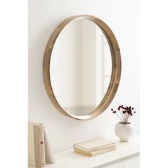 a round mirror sitting on top of a white table next to a vase with flowers