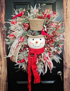 a christmas wreath with a snowman wearing a top hat and scarf on the front door