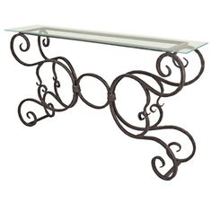 an iron and glass console table with scroll designs on the top, against a white background