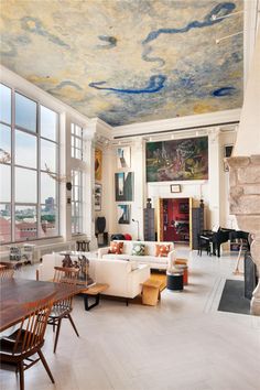 a living room filled with furniture and a fire place next to a large painting on the ceiling