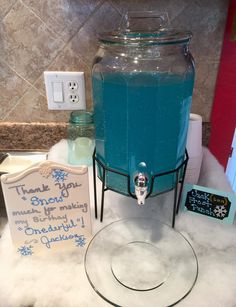 a blue beverage dispenser sitting on top of a counter next to a sign