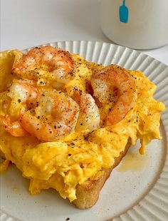 an omelet with shrimp and eggs on a paper plate next to a cup