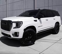 a white truck is parked in front of a building with black rims and tires