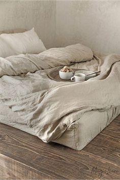 an unmade bed sitting on top of a wooden floor next to pillows and blankets