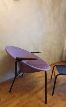 a purple surfboard sitting on top of a wooden table next to a blue chair