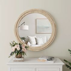 a white dresser topped with a mirror and flowers